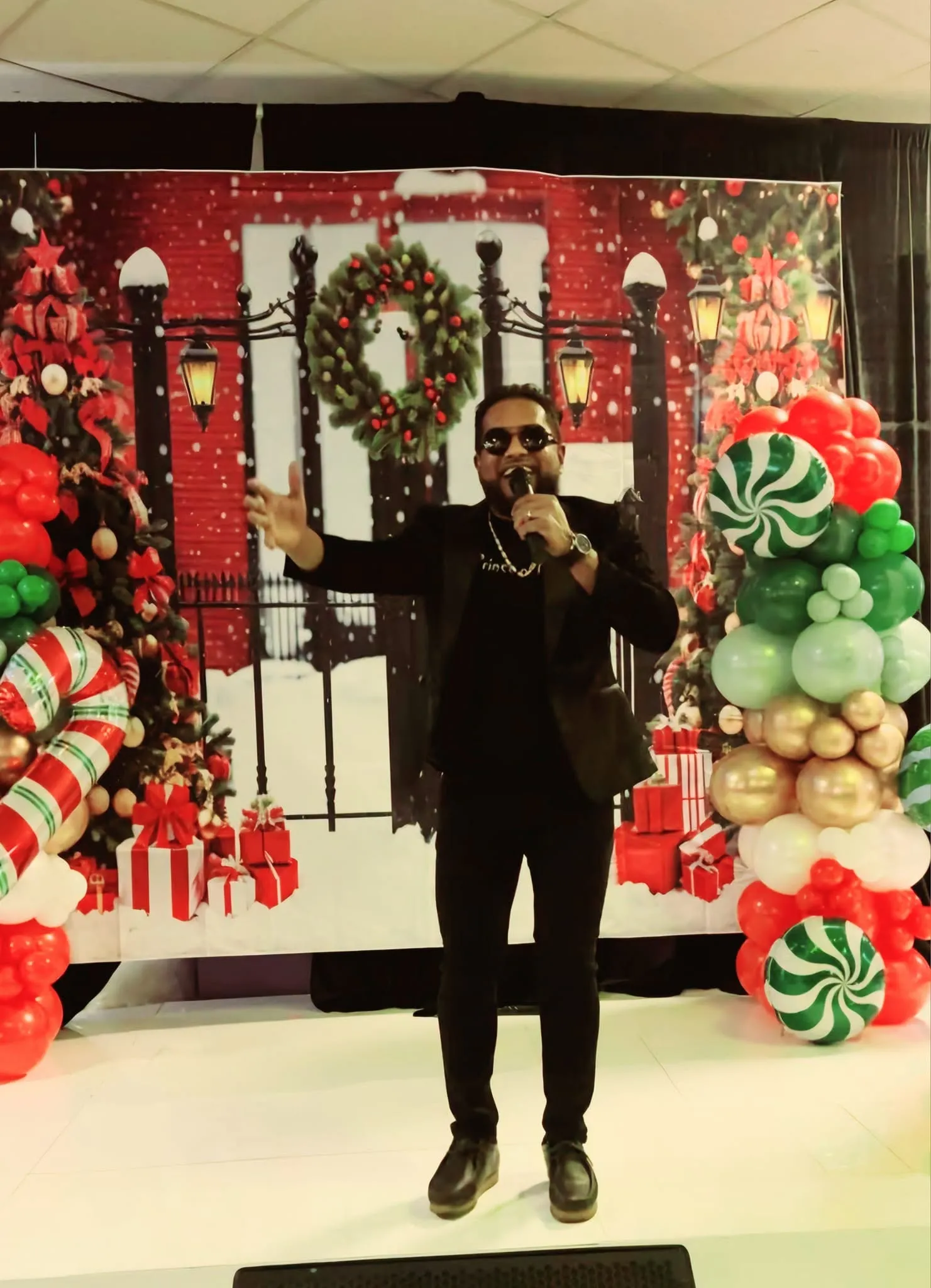 A performer singing on stage in front of a festive backdrop